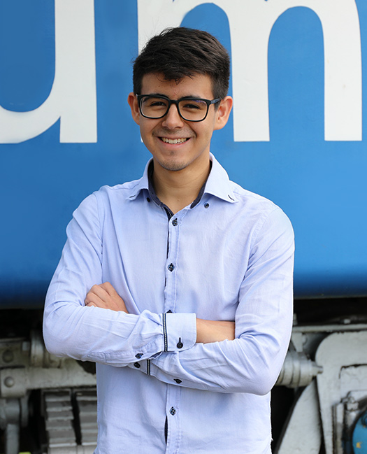 Homem de óculos, sorrindo e de braços cruzados | Rumo